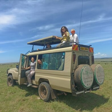 Keshi Tours clients on a safari Land Cruiser posing for a photo in the Masai Mara National Reserve